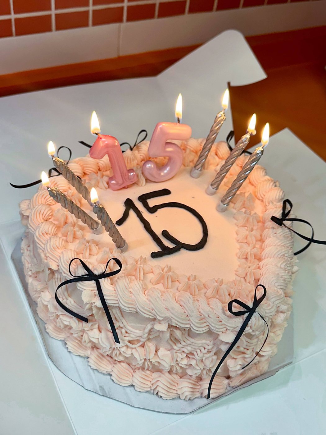Pastel de cumpleaños rosa con velas y lazos, para unos 15 años